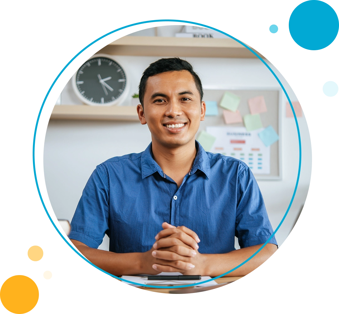 Hombre sonriente con las manos juntas sobre un escritorio